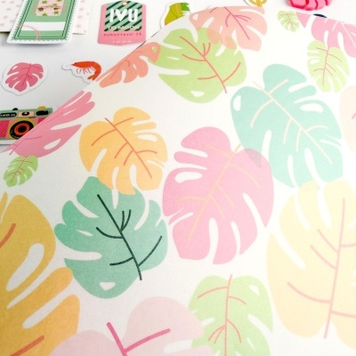 Papel decorado com folhas coloridas e autocolantes variados numa mesa branca