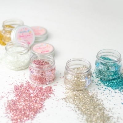 Frascos pequenos de glitter colorido em superfície branca