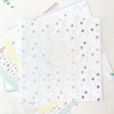 Folha de acetato com estrelas holográficas sobre folhas de papel decorativo e ferramentas de artesanato