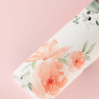Rolo de tecido floral sobre superfície rosa