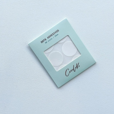 Embalagem azul clara com pontos adesivos brancos autocolantes visíveis e texto impresso