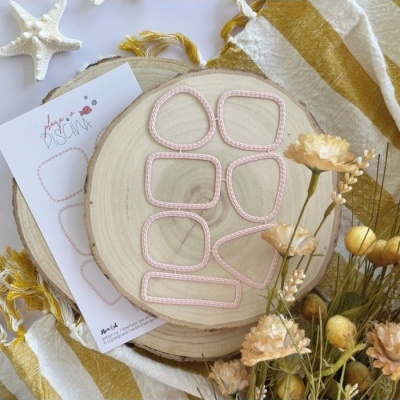 Modelos ou moldes rosa claro em tábua de madeira rodeados por flores secas e cartão com texto