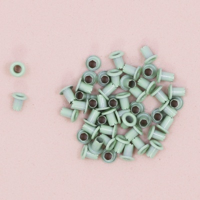 Ilhós metálicos verdes sobre fundo rosa