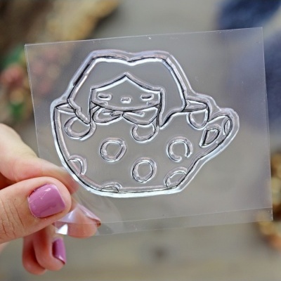 Placa transparente com relevo prateado de chávena com bolinhas e face feminina