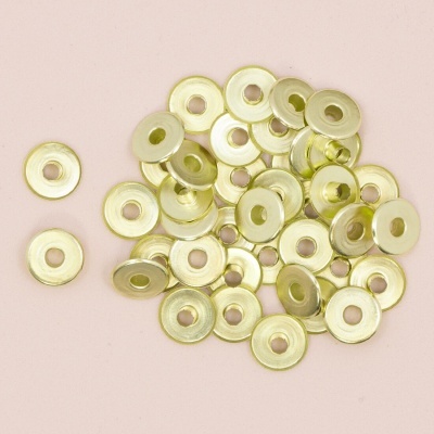 Argolas metálicas douradas pequenas sobre fundo rosa claro