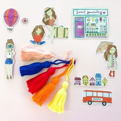 Cinco borlas coloridas e recortes de papel com ilustrações variadas sobre fundo branco.