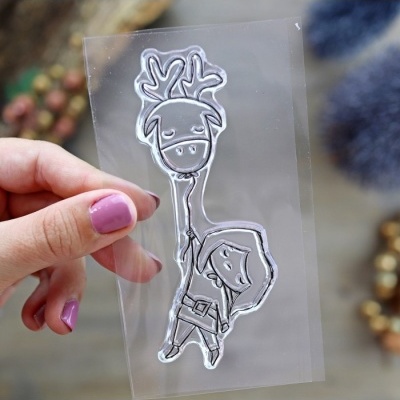 Carimbo transparente com desenho de rena e personagem em fundo desfocado