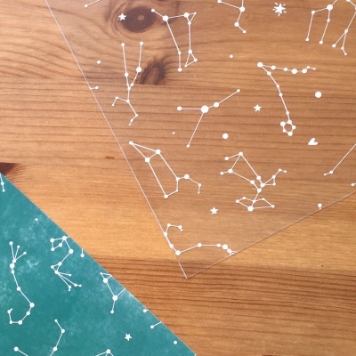 Papéis transparentes com constelações brancas sobre madeira
