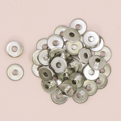 Ilhós metálicos prateados redondos com buraco central sobre fundo rosa