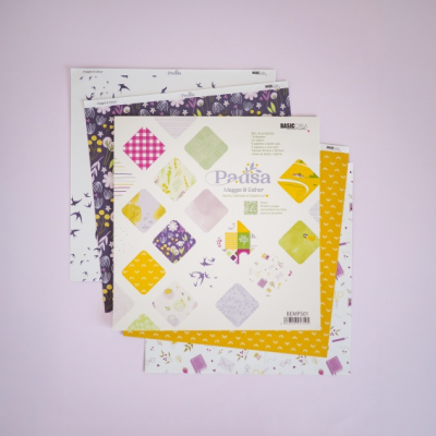 Folhas de papel decorativo coloridas e estampadas sobre fundo rosa