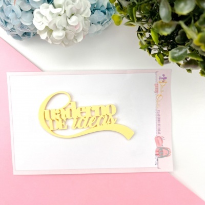 Cartão branco com texto amarelo 'Quadro de Ideias' em relevo em fundo rosa e branco com flores e plantas