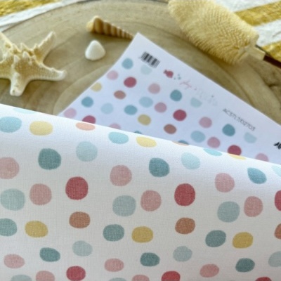 Tecido com padrão de bolinhas coloridas em tom pastel sobre madeira clara com decoração marinha