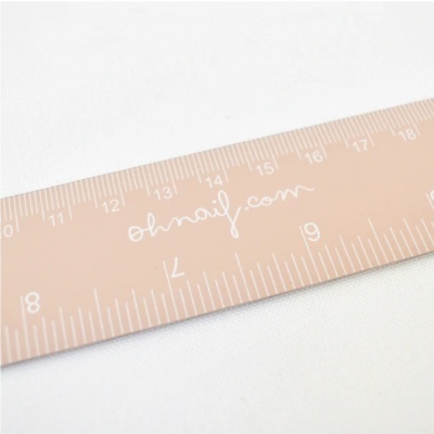 Régua bege com marcações e texto branco sobre superfície branca