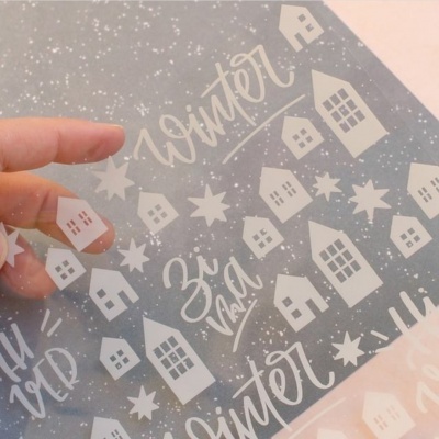 Folha transparente com padrão branco de casas e estrelas e texto manuscrito