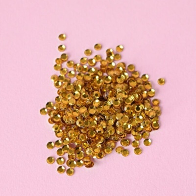 Pequenas lantejoulas douradas redondas sobre fundo rosa