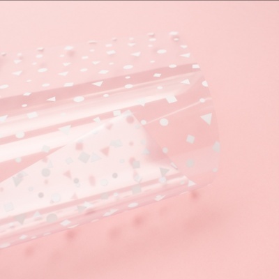 Rolo de papel transparente com padrão branco sobre fundo rosa