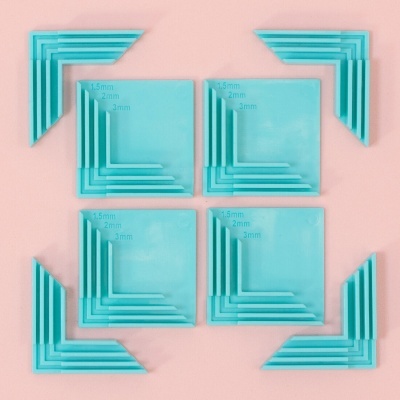 Esquadros de silicone azuis translúcidos para canto de móveis, com marcações de medidas, sobre fundo rosa