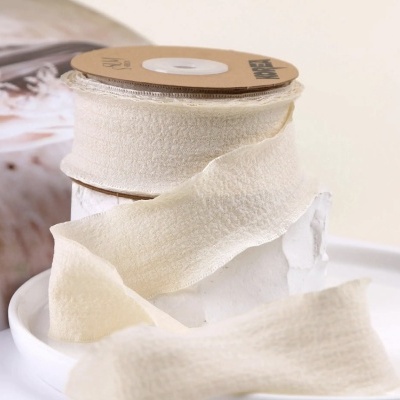 Rolo de fita creme textura rugosa sobre bobina de cartão castanho em recipiente branco