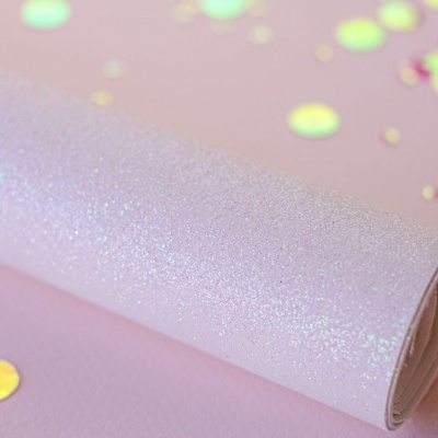 Rolo de papel brilhante branco com lantejoulas coloridas em fundo rosa