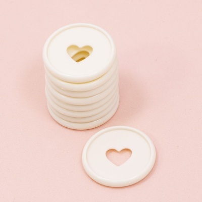 Discos brancos com recorte de coração sobre fundo rosa