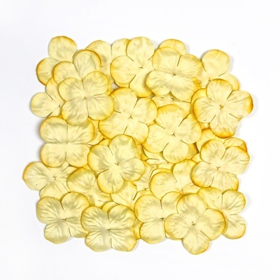 Flores artificiais amarelas claras com cinco pétalas numa superfície branca