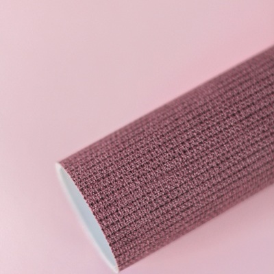 Rolo de papel autocolante texturizado cor vinho sobre superfície rosa