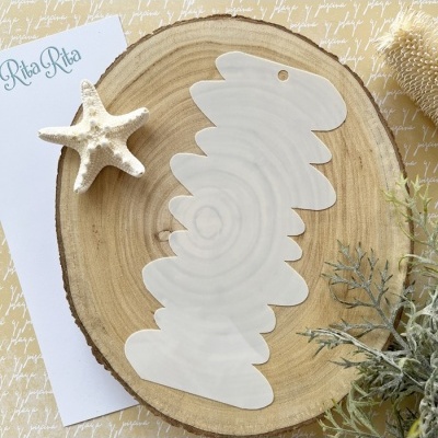 Peça branca irregular sobre tronco de madeira com estrela-do-mar, cartão Rita Rita e plantas secas