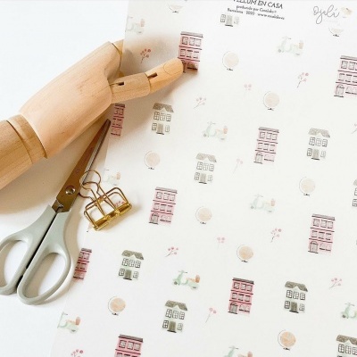 Folha decorativa com padrão de casas e motos, mão de madeira, tesoura e clipe