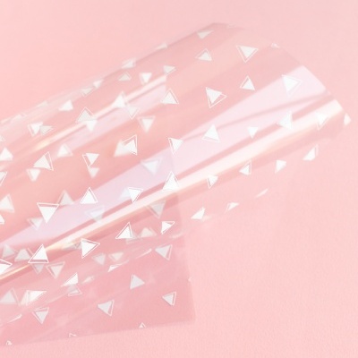 Folha de plástico transparente com triângulos brancos sobre fundo rosa