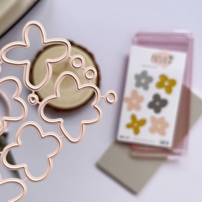 Organizador rosa com recortes de flores em primeiro plano e bloco de notas com adesivos de flores ao fundo