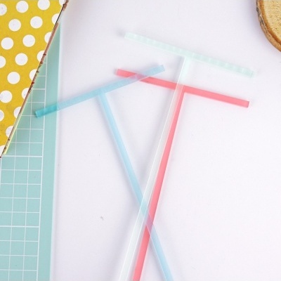 Canudos reutilizáveis de plástico translúcido colorido sobre superfície branca perto de notebook amarelo e superfície verde