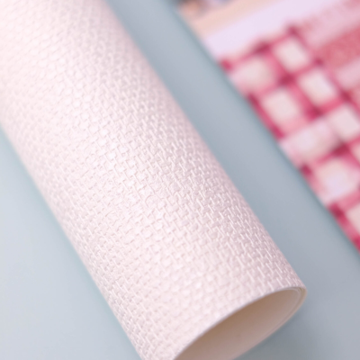 Rolo de papel texturizado branco com padrão geométrico em relevo sobre superfície azul clara