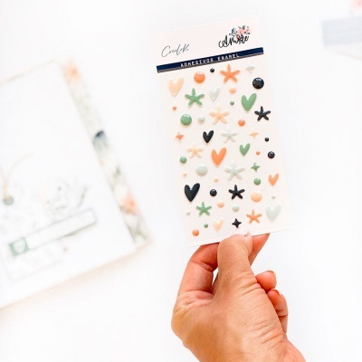 Mão segurando cartão de adesivos em relevo coloridos sobre fundo branco