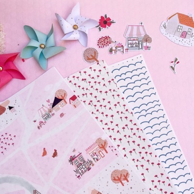 Folhas decorativas com padrões diversos e cataventos de papel coloridos sobre fundo cor-de-rosa.