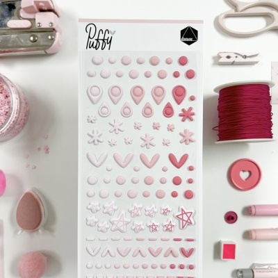 Cartela de autocolantes 3D Puffy com várias formas em tons de rosa e vermelho em fundo branco com materiais de artesanato ao redor