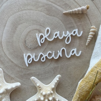 Palavras decorativas brancas sobre superfície bege com estrelas do mar e conchas