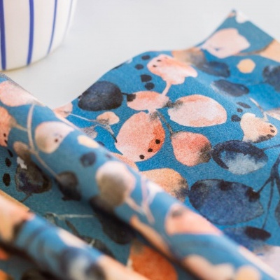 Tecido estampado colorido com padrão de pássaros azul, laranja e rosa sobre fundo azul