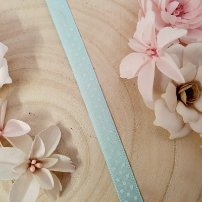 Fitas azuis com bolinhas e flores artificiais em madeira clara