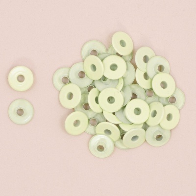 Discos pequenos creme com furo central sobre fundo rosa