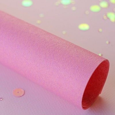 Rolo de papel decorativo cor-de-rosa com lantejoulas holográficas num fundo rosa
