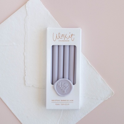 Pacote branco com seis velas lavanda e selo decorativo com ramo de flores