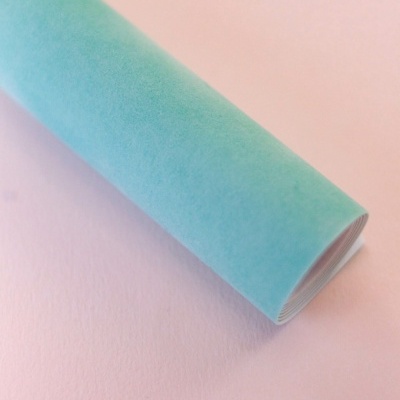 Rolo de papel azul turquesa sobre superfície rosa