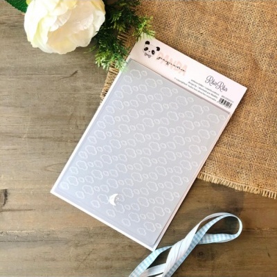 Stencil plástico transparente padrão de nuvens com etiqueta branco em superfície de madeira com flor e fita azul