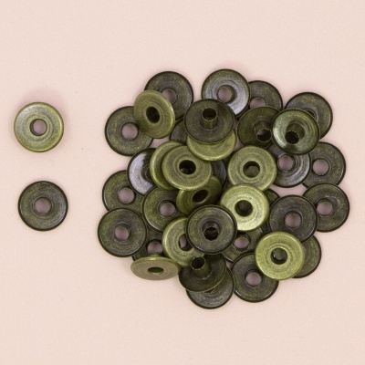 Peças metálicas redondas verde-oliva com buraco central sobre fundo bege