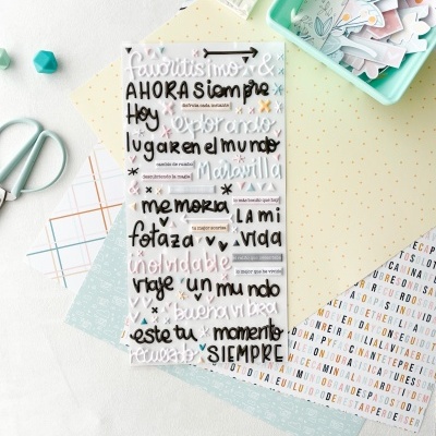 Autocolantes transparentes com texto em espanhol, folhas decorativas e pastas verdes sobre uma mesa branca