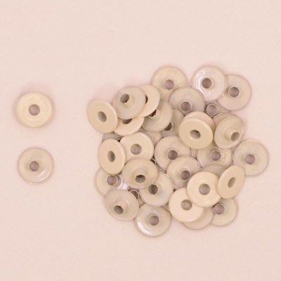 Botões de plástico bege redondos com um orifício central sobre fundo bege