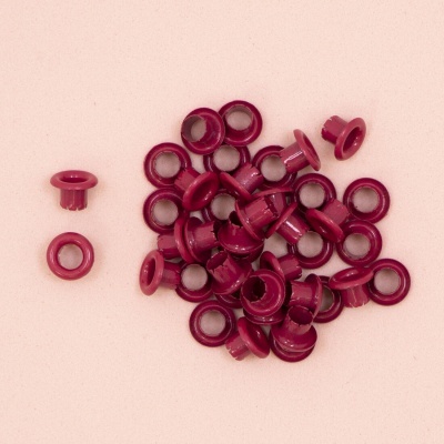 Ilhóses plásticos bordô sobre fundo rosa claro