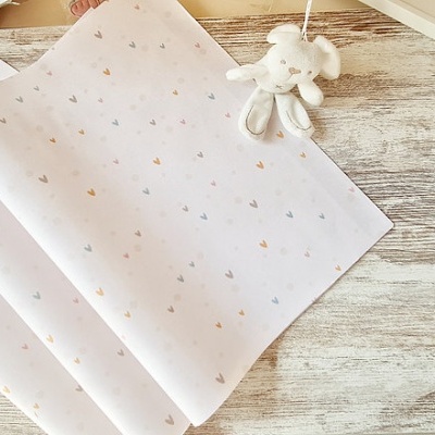 Toalhas de tecido branco com pequenos padrões coloridos sobre mesa de madeira clara