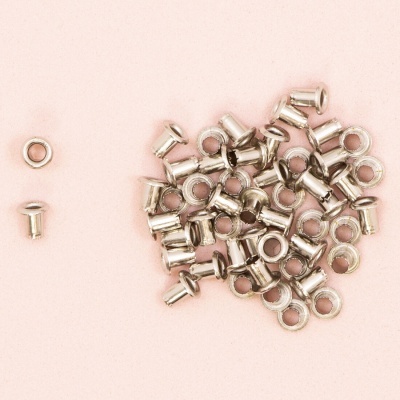 Ilhós de metal prateado sobre fundo rosa claro