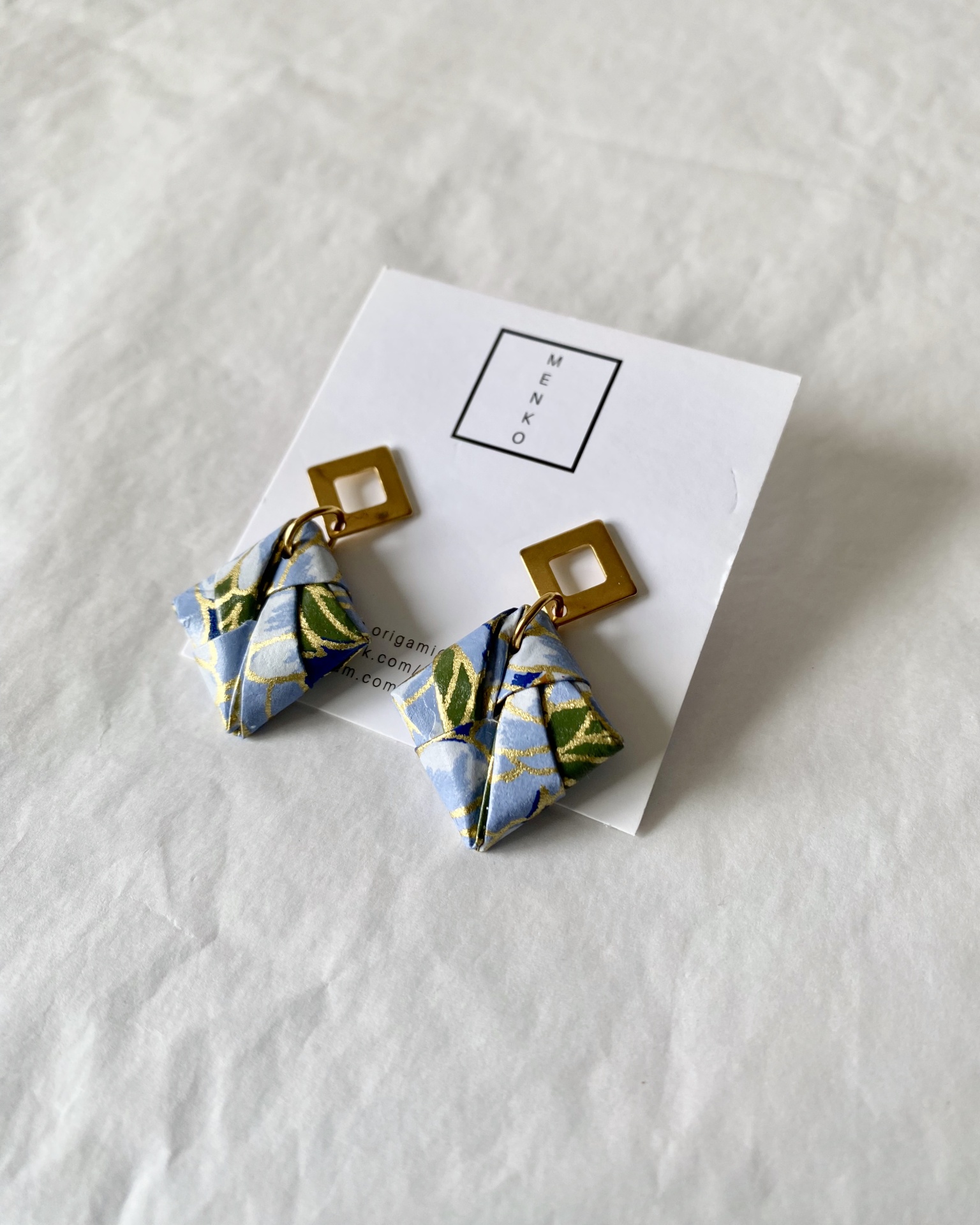 Brincos Sonobe Brincos pendentes dourados com tecido padrão floral azul e verde no cartão MENKO